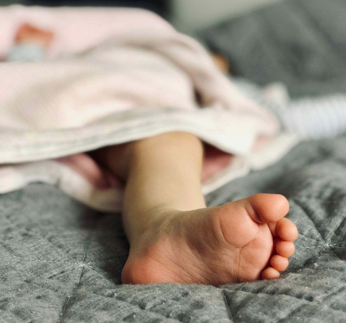 babys feet on white textile
