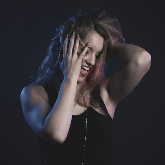 woman in black tank top covering her face with her hands
