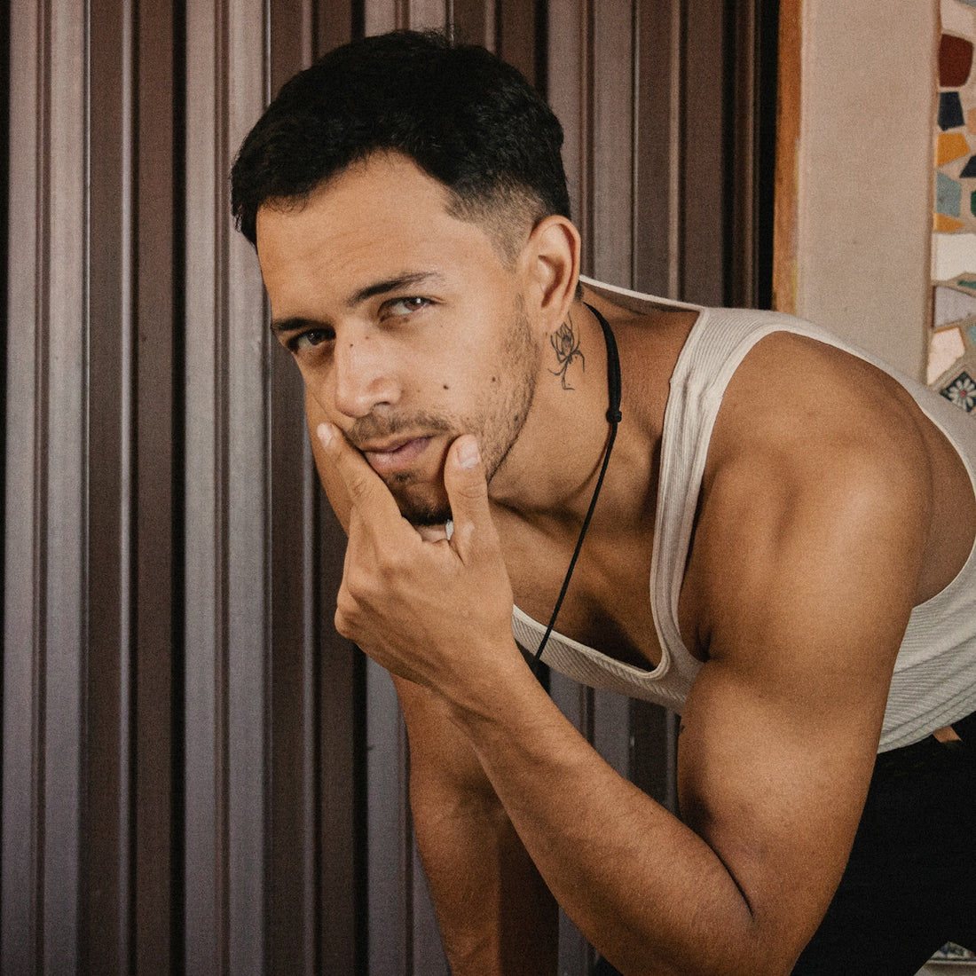 a man leaning against a wall with his hand on his chin