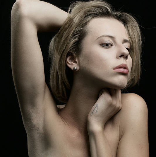 a nude woman posing for a picture with her arm behind her head