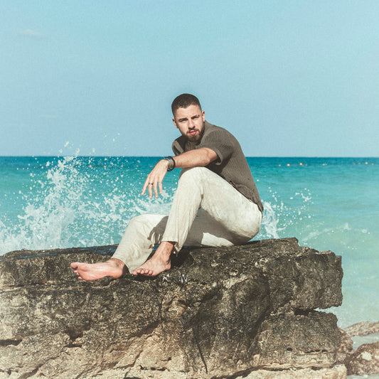 a man sitting on top of a rock near the ocean