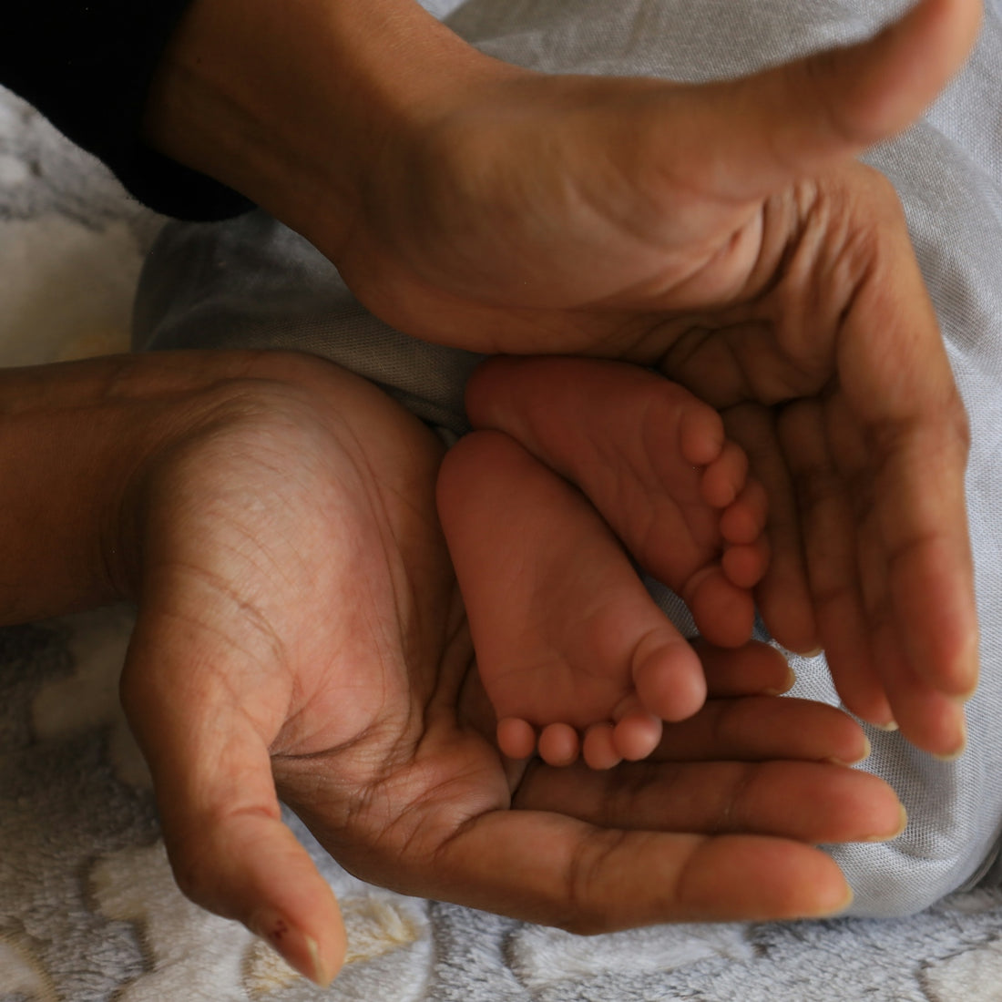 Hands cradling a baby's tiny feet.