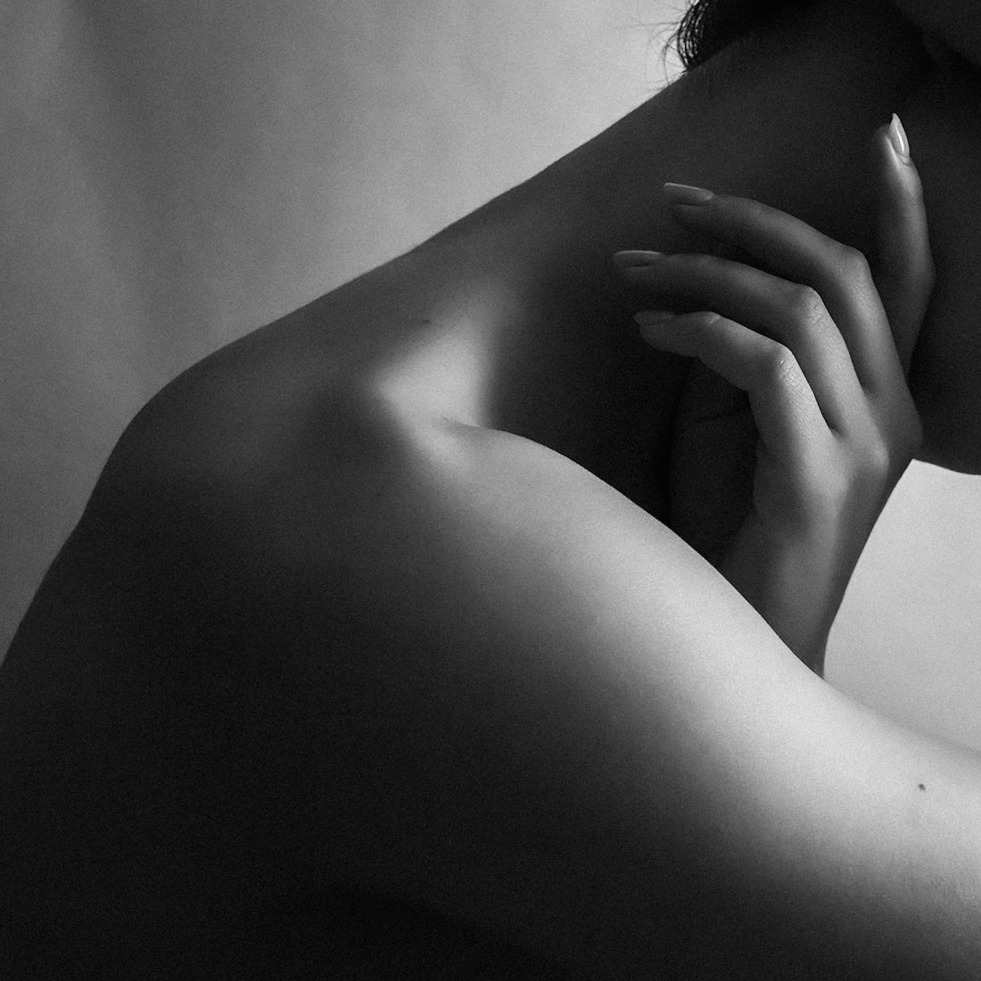 A person's shoulder, neck, and hand in black and white.